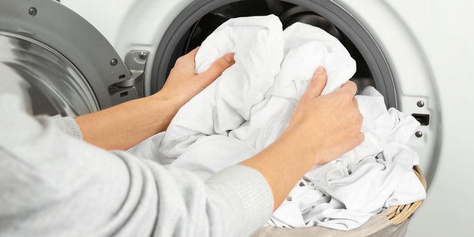 Hands getting out clean clothes from washing machine