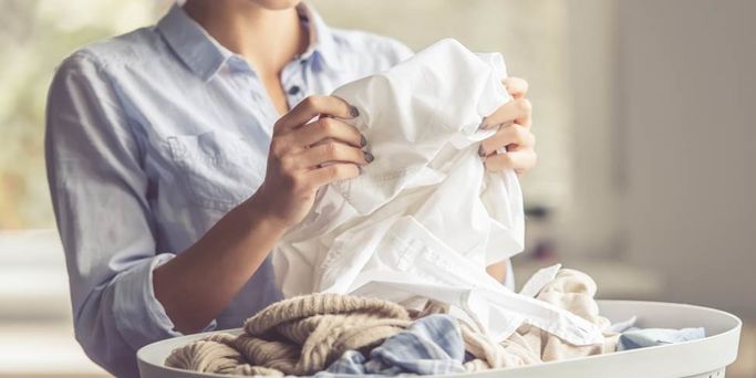 Woman folding clean clothes thanks to Soda Solvay