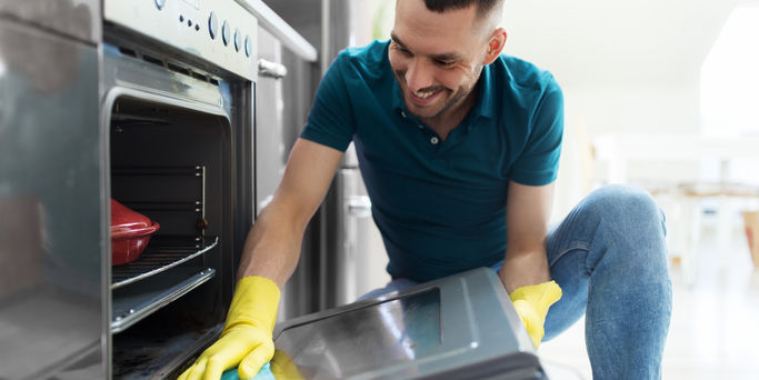 Man cleaning oven door kitchen
