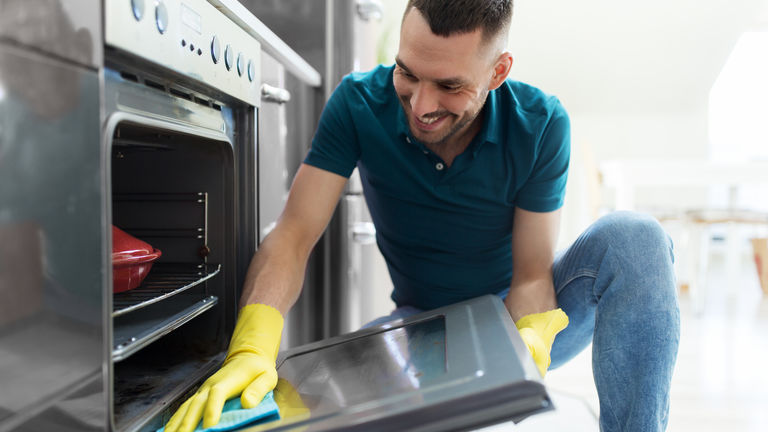Man cleaning oven door kitchen
